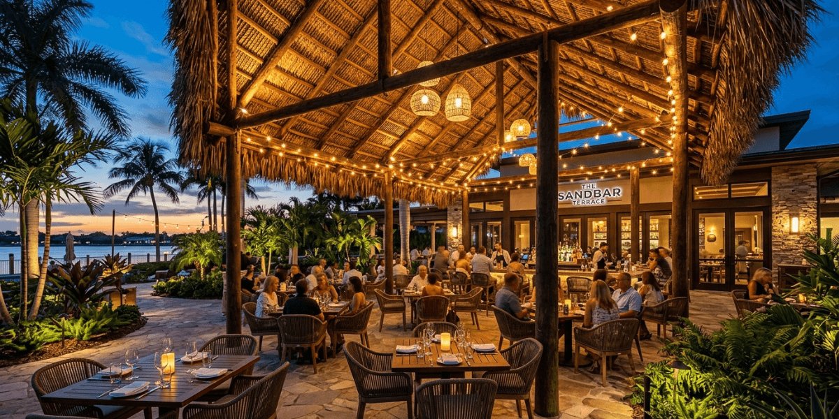 A beachside restaurant at sunset, with vibrant orange and pink skies reflecting on the calm ocean waters.